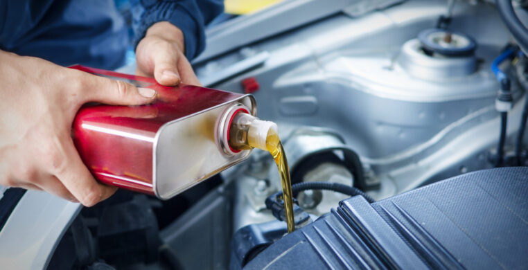 Mechanic changing engine oil on car vehicle.